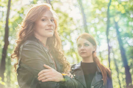 Low angle on self-confident young girl and her jealous girlfriend during a walk in the forest
