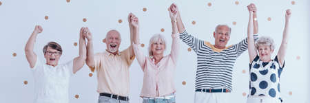 Group of happy senior friends having fun together during party and holding handsの写真素材