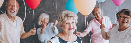 Happy senior people with colorful balloons celebrating their friend's birthdayの写真素材