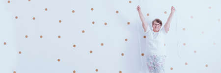 Positive grandmother enjoying life, standing against white wall with gold dotsの写真素材