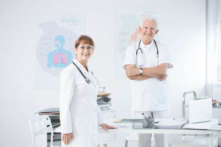 Two doctors in uniforms standing at the office and talking about a patientの写真素材
