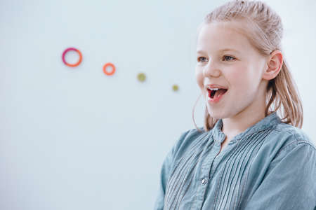 Young girl with blonde hair enjoying being at a speech therapy classの写真素材