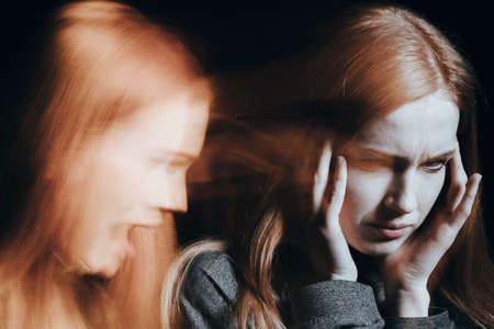 Sick woman with schizophrenia hearing voices. Blurred face on black background.の写真素材