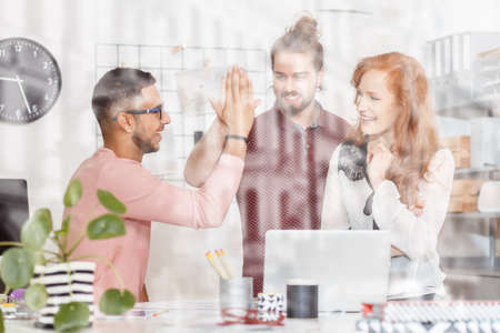 Spanish man and team lead giving a high five in business office