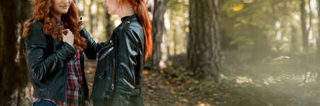 Close-up of lesbian girl touching girlfriend's hair during a walk in the forest