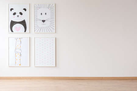 Bright empty room interior for newborn baby with four posters with animals and dots hanging on the...
