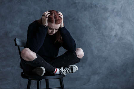 Worried teenager with a headache against dark background with copy spaceの写真素材
