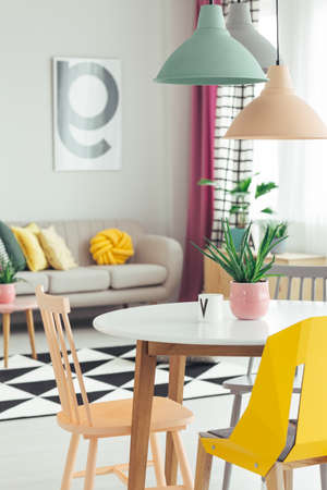 Close-up of colorful lamps hanging above round dining table in bright, open space apartment interiorの写真素材