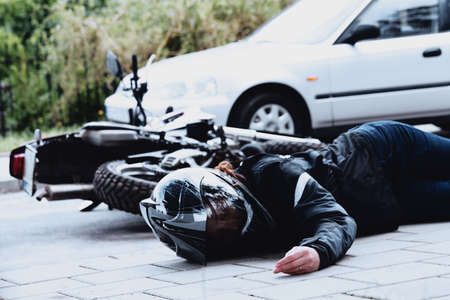 Dead motorcyclist lying next to her motorcycle and car after a collision on the roadの写真素材