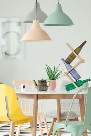 Close-up of wine bottles, aloe plant and green kettle standing on a round, wooden dining table in dining room interiorの写真素材
