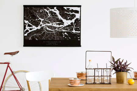 Close-up photo of glass bottles placed on oak table with metal bowls, potted plant and lemon in dining room interiorの写真素材