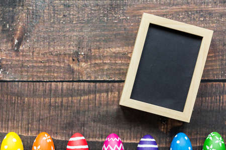 Black picture in wooden frame and colorful easter eggsの写真素材