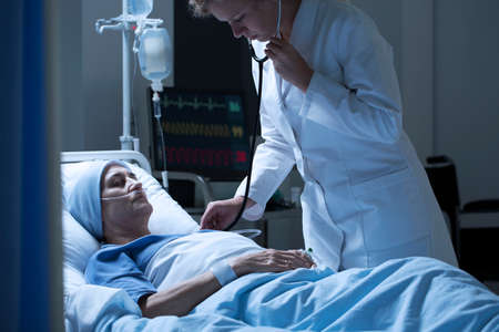 Doctor in white uniform examining sick woman with cancer in the health centerの写真素材