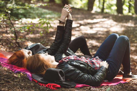 Two ginger lesbians lying on the blanket, holding hands in the forestの写真素材
