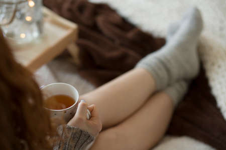 Close-up of woman drinking hot tea in the bedroom during winter weather