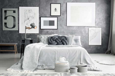 Simple gallery on grey raw wall in bedroom interior with boxes placed by the bedの写真素材