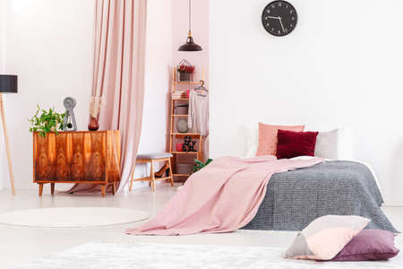 Feminine bedroom interior with pink blanket on gray bed and cabinet next to a walk-in closetの写真素材