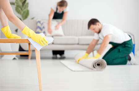 Professional cleaning crew at work. Person in yellow gloves wiping the table
