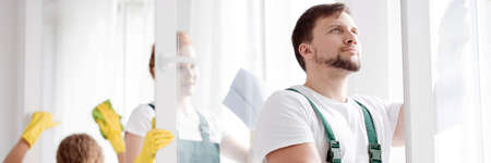 Panorama of professional cleaners wiping windows in an office building with clothの写真素材