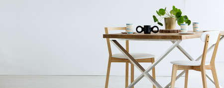 Copy space on white wall in empty dining room interior with chairs at wooden tableの写真素材