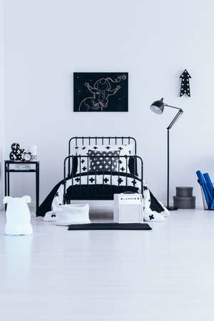 Monochromatic bedroom interior for a little astronaut with metal bed, black lamp and poster on white wallの写真素材