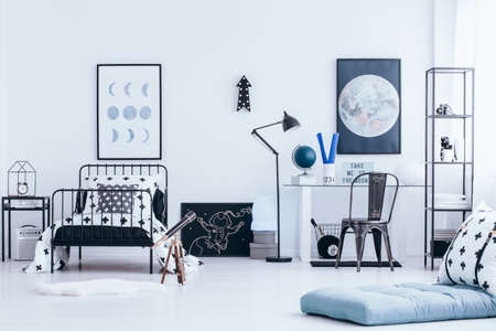 Bright kid's bedroom interior with study space, lunar posters on the wall and telescope next to the bedの写真素材