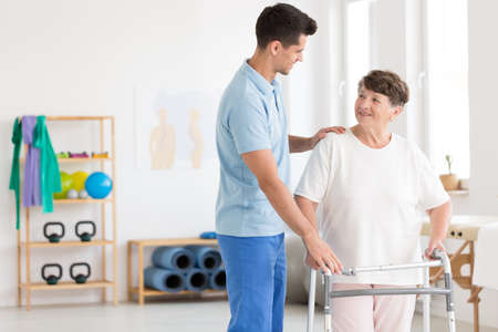 Caring physiotherapist supporting an elderly woman with a walking frameの写真素材