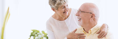 Panorama of happy grandmother hugging her smiling husband in the morning