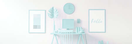 Panorama of desk with monstera leaf between posters in pastel blue home office interior with clockの写真素材