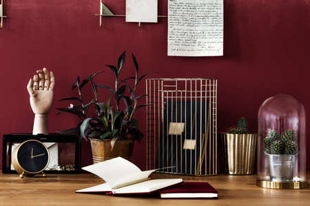 Close-up of books on the desk with cactus and gold clock in work area with red wallの写真素材