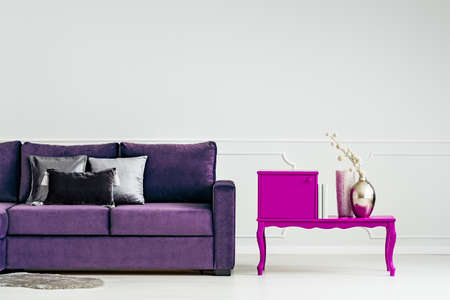 Pink, creative table and velvet couch set on an empty wall in living room interiorの写真素材