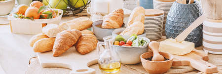 Olive oil between croissants, butter and mortar with pestle on dining tableの写真素材