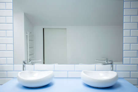 White washbasins against brick wall with mirror in simple bathroom interior