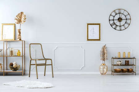 Gold leaves and chair against white molding wall with poster in luxurious living room interiorの写真素材