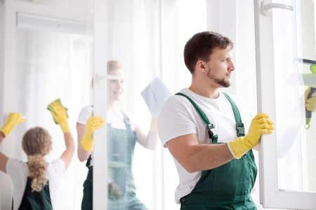 Man in protective clothing and yellow gloves focusing on cleaning workの写真素材