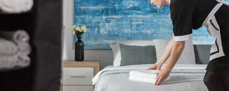 Panorama of maidservant arranging towels on a bed according to hotel standardsの写真素材