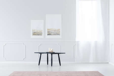 Candles on wooden table against white wall in simple bright living room interior with windowの写真素材