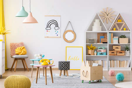 Wooden crate and yellow pouf in colorful kid's playroom interior with poster and patterned stoolの写真素材