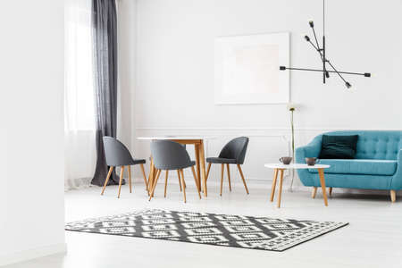 Simple living room interior with dining table, chairs and blue sofa