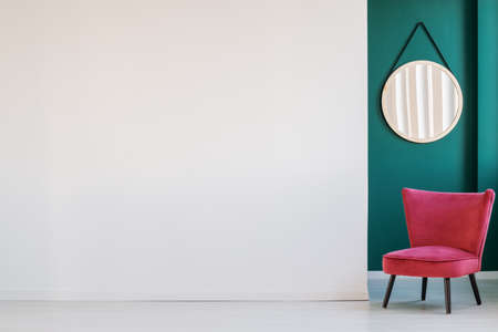 White, empty wall, round mirror and pink armchair in a corridor interiorの写真素材