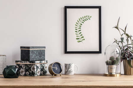 Patterned boxes and cactus standing on a wooden table in a room with poster on the wall