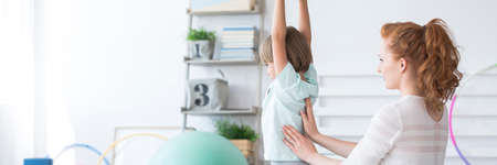 Physiotherapist massaging boy's beck during corrective gymnastics