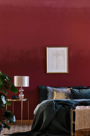 Luxurious bedroom interior with dark red wall, king-size bed and elegant lampの写真素材