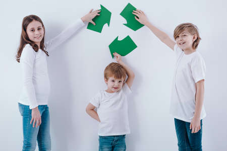 Children isolated on a white background holding a green recycling symbol