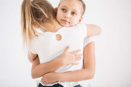 Close-up portrait of an upset girl's back and her sister comforting her with a hugの写真素材