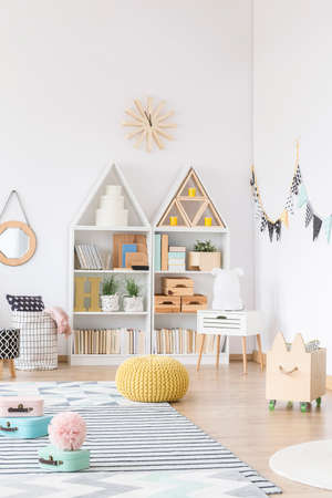 Yellow pouf and wooden box in white kid's playroom interiorの写真素材