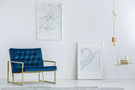 Classy furniture and framed map posters on a white wall in a luxurious, designer living room interior with minimalist decorの写真素材