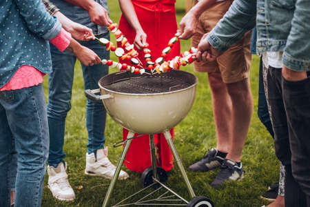 Group of people grilling shashliks during garden partyの写真素材
