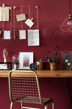 A gold chair and wooden desk with ornaments in red room interior with ombre wallの写真素材