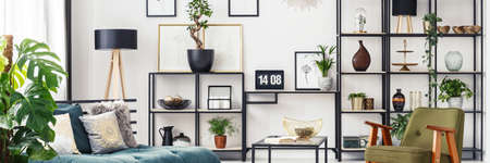 White living room interior with decorations on metal rack and laptop on home office desk